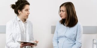 Ciąża a choroby przenoszone drogą płciową: które badania warto wykonać, jak leczyć infekcje i jak chronić zdrowie płodu Ciężarna kobieta rozmawia z lekarką w gabinecie o zdrowiu w ciąży