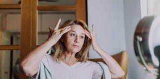 Suchość pochwy w menopauzie – skuteczne metody leczenia i poprawy komfortu współżycia Dojrzała kobieta w łazience wykonuje codzienną pielęgnację twarzy