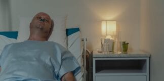 Samotność w chorobie przewlekłej: dlaczego wsparcie społeczne leczy równie mocno jak leki Mężczyzna leżący w szpitalnym łóżku z kaniulą donosową przy lampce