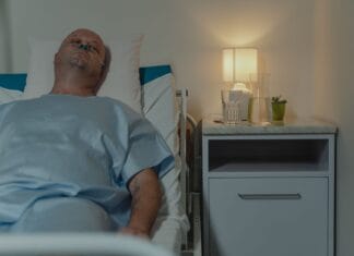 Samotność w chorobie przewlekłej: dlaczego wsparcie społeczne leczy równie mocno jak leki Mężczyzna leżący w szpitalnym łóżku z kaniulą donosową przy lampce