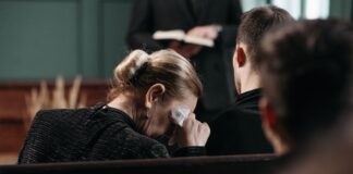 Utrata ciąży a zdrowie psychiczne: etapy żałoby, mity i sposoby szukania profesjonalnej pomocy Zapłakana kobieta ociera łzy podczas ceremonii pogrzebowej w pomieszczeniu