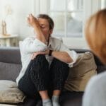Kobieta ociera łzy podczas sesji terapeutycznej na kanapie