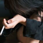 Zbliżenie na młodą kobietę trzymającą papierosa w pomieszczeniu